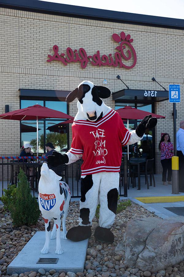 Chick-fil-A cow mascot stands with wolf